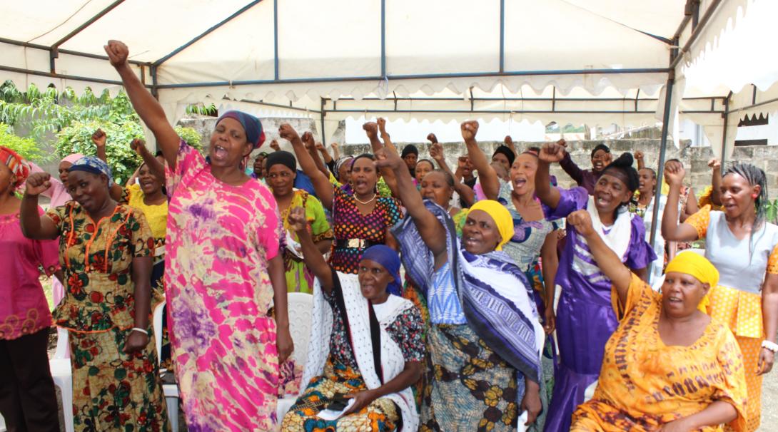 Tanzanian women stand up during a women's empowerment speech made by a local organisation.